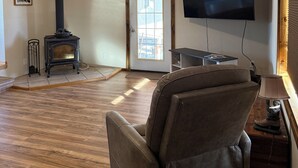 A living room with a fireplace, a television, and a sofa. - Charming 3-bedroom house with AC, WiFi (Columbia Falls)