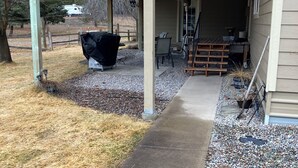 A covered outdoor area with a concrete path leading to a wooden deck, a barbecue grill, and a seating area with chairs and a table. - Charming 3-bedroom house with AC, WiFi (Columbia Falls)