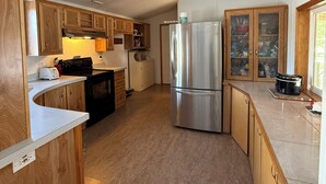 A modern kitchen with wooden cabinets, stainless steel appliances, and a tiled backsplash. - Charming 3-bedroom house with AC, WiFi (Columbia Falls)