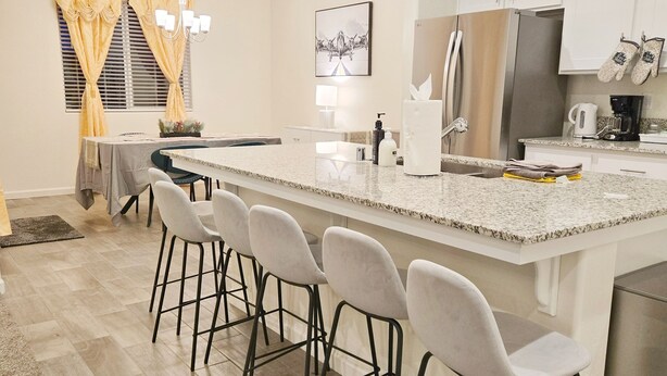 Une cuisine moderne dotée d’un grand îlot central, de tabourets de bar et d’un coin repas avec une table et des chaises.
