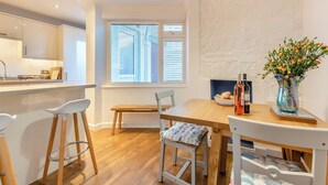 A modern kitchen with a wooden countertop, a dining table with chairs, and a window with blinds. - 3 bedroom accommodation in New Quay (New Quay)