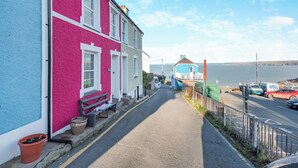 A narrow street with colorful houses, a bench, and parked cars. - 3 bedroom accommodation in New Quay (New Quay)