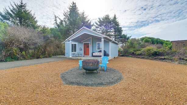 A small house with a gravel driveway, a fire pit, and two blue chairs. - 1/2 Mi to Beach: Home w/ Patio in Ocean Shores (Ocean Shores)