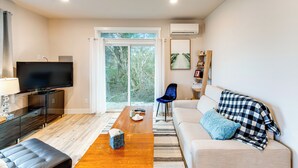 A modern living room with a flat-screen TV, a wooden coffee table, a sofa with a checkered throw, and a blue chair. - 1/2 Mi to Beach: Home w/ Patio in Ocean Shores (Ocean Shores)