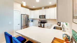 A modern kitchen with white cabinets, stainless steel appliances, and a large island. - 1/2 Mi to Beach: Home w/ Patio in Ocean Shores (Ocean Shores)
