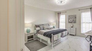 Una camera da letto con un letto, comodini, una scrivania, una sedia e una finestra con tende.