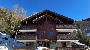 A multi-story wooden building with balconies, a stone base, and a sign indicating it is a hotel.