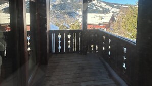 A wooden balcony with a view of snow-covered mountains.