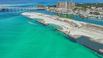 An aerial view of a coastal area with a marina, a large hotel, and a bridge.