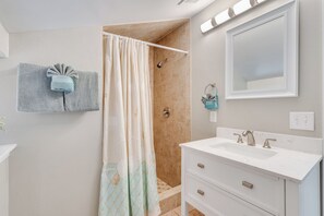 A bathroom with a shower, a sink, and a mirror.