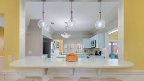 Een moderne keuken met een centraal eiland, roestvrijstalen apparatuur en uitzicht op de aangrenzende woonkamer.