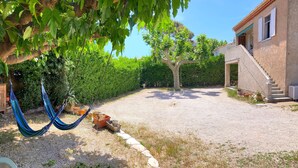 A courtyard with a hammock, a gravel path, and a building with a staircase.