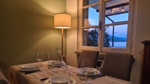 Una mesa de comedor dispuesta con platos, vasos y cubiertos, una lámpara y una ventana con vistas al exterior.
