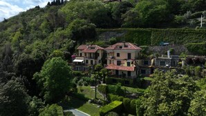 Una villa en una ladera con varias construcciones, rodeada de vegetación exuberante y un cielo despejado.