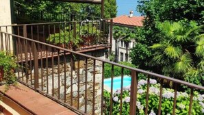 Un balcón con vistas a una piscina y follaje verde.