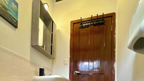 A bathroom with a white toilet, a wooden door, and a mirror above the sink. - Master Suite Platinum #1 (San Pedro Sula)