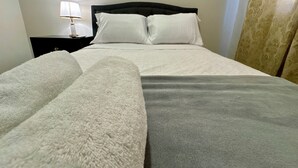 A neatly made bed with a grey and white duvet, a black headboard, and a bedside lamp. - Master Suite Platinum #1 (San Pedro Sula)