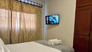 A hotel room with a bed, a TV mounted on the wall, and a wooden wardrobe. - Master Suite Platinum #1 (San Pedro Sula)