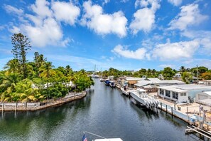 A marina with boats docked, a clear sky, and a waterway lined with trees and buildings.