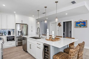 A modern kitchen with white cabinetry, stainless steel appliances, and a central island with seating. - Large Waterfront Escape, Water Views in Key Largo with Boat Dock (Tavernier)