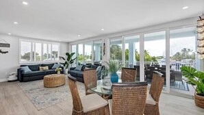 A spacious living area with a dark-colored sofa, a round coffee table, wicker chairs, and a glass-top dining table. - Large Waterfront Escape, Canal Views (Tavernier)