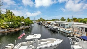 A marina with boats docked, a clear sky, and a tropical setting with palm trees. - Large Waterfront Escape, Canal Views (Tavernier)