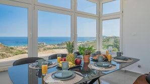 Un coin repas avec une table mise pour le petit-déjeuner, donnant sur un paysage côtier.