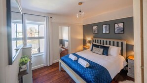 A bedroom with a bed, bedside tables, a window, and a view of the outside. - Swift Host | Central | 3 Bedrooms | Parking (Norwich)
