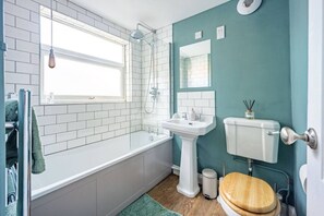 Ein Badezimmer mit Badewanne, Waschbecken, Toilette und einem Fenster.