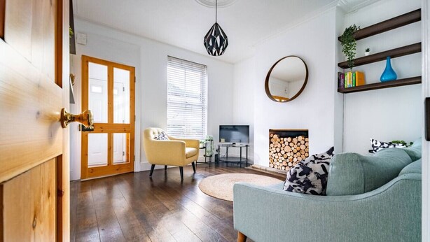 A living room with a sofa, a chair, a TV, a fireplace, and a bookshelf. - Swift Host | Stylish City Terrace | Parking (Norwich)