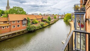 A canal with buildings on one side and a church spire in the background. - Swift Host | Fishergate 2 bed | River View (Norwich)