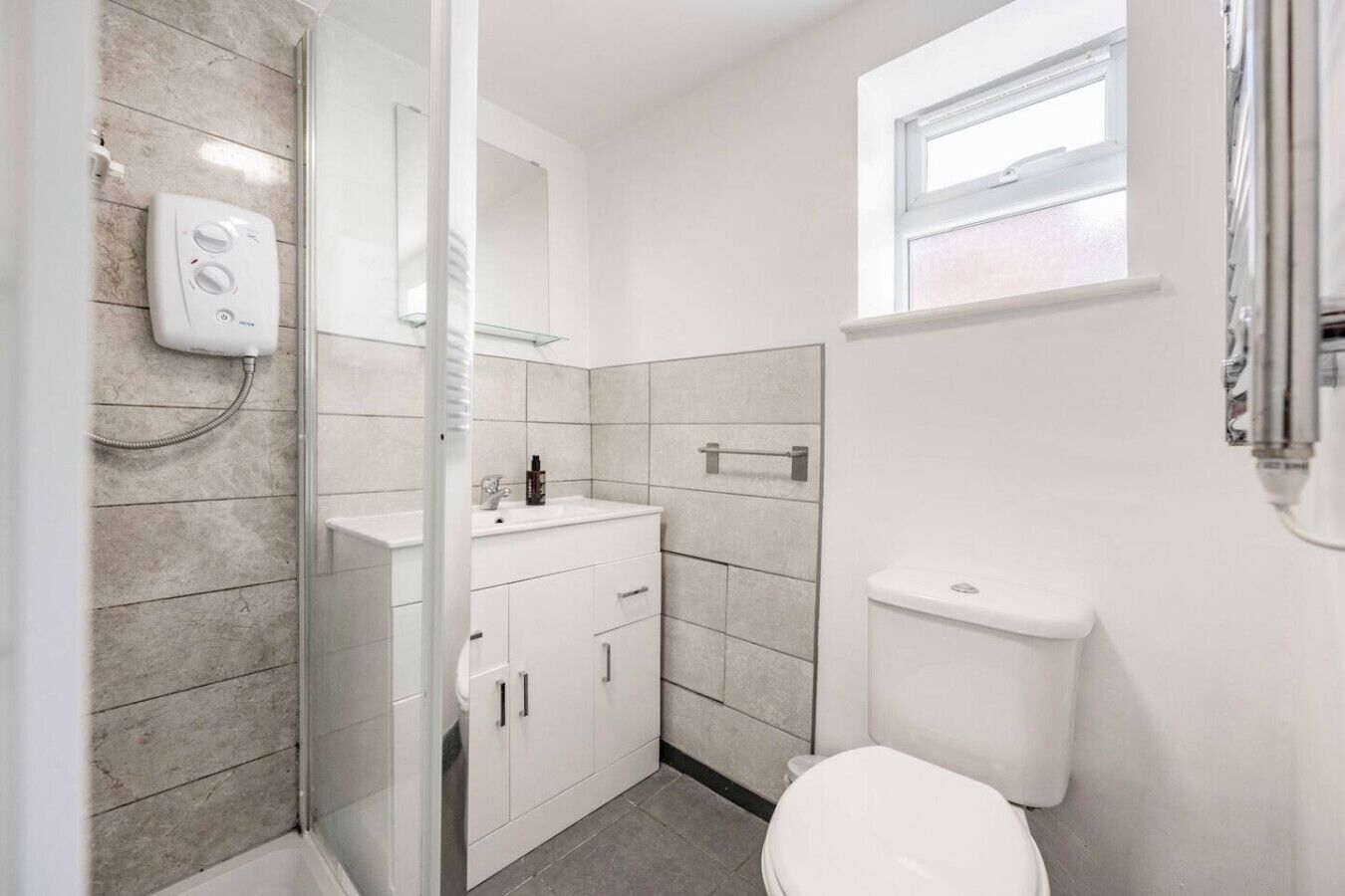 Un bagno moderno con cabina doccia in vetro, lavandino bianco e servizi igienici.
