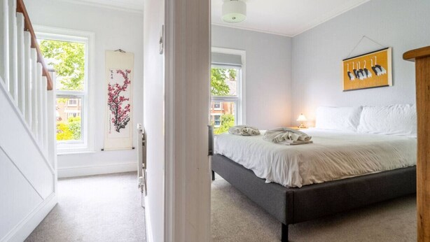 Une chambre avec un grand lit, une tête de lit en bois et une fenêtre donnant sur la forêt.