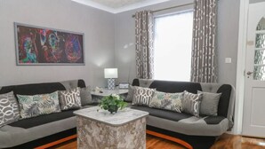 A modern living room with a grey sofa set, a marble coffee table, and a painting on the wall. - Swift Host: 2 bed 2 baths | On-street Free parking (Norfolk East Coast)