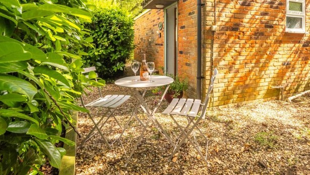 A small brick building with a window and a door, surrounded by greenery and a gravel path. - Swift Host The Nook Rural Barn near the Norfolk Broads (Norfolk Broads)