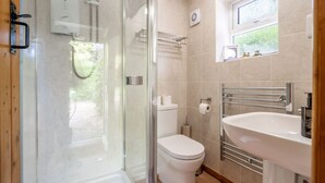 A modern bathroom with a glass-enclosed shower, a toilet, and a sink with a towel rack. - Swift Host The Nook Rural Barn near the Norfolk Broads (Norfolk Broads)