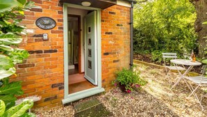 A small brick building with a door open, a sign reading "The Nook", and a garden area with a table and chairs. - Swift Host The Nook Rural Barn near the Norfolk Broads (Norfolk Broads)