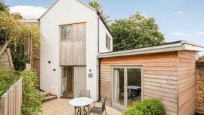 Ein zweistöckiges Haus mit einer Terrasse, komplett mit Tisch und Stühlen.