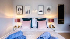 Ein Hotelzimmer mit einem großen Bett, zwei Nachttischen und drei gerahmten Bildern an der Wand.