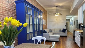 A dining area with a wooden table, a vase of yellow tulips, and a blue cabinet with glass doors. - Charming 2 BR/2 bath in Historic District - Rent 1 Suite or Both/8-16 people! (Troy)