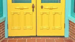 A bright yellow double door with glass panels, each displaying a tree silhouette and the words "Walnut" and "Suites" respectively. - Charming 2 BR/2 bath in Historic District - Rent 1 Suite or Both/8-16 people! (Troy)