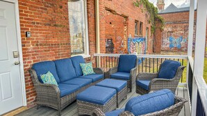 A covered porch with wicker furniture and a brick wall. - Charming 2 BR/2 bath in Historic District - Rent 1 Suite or Both/8-16 people! (Troy)