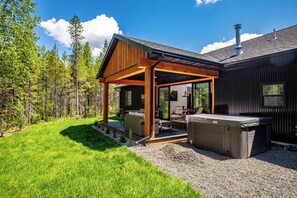A modern house with a covered patio, outdoor seating, and a hot tub.