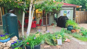 A patio area with a red table and chairs, surrounded by potted plants and a wooden fence. - Raven's Grotto (Flagstaff)