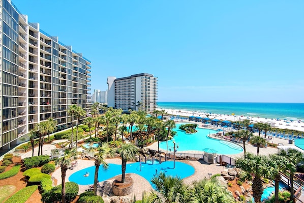 A resort with a large swimming pool, palm trees, and a beach view.