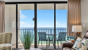 Ein Balkon mit Blick auf den Ozean, inklusive Tisch, Stühle, einer Couch und einer Lampe.