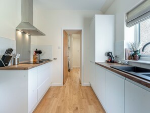 A modern kitchen with white cabinetry, a wooden countertop, and a stainless steel range hood. - Newbigging Farm Cottage (Auchterarder)