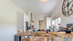 Une cuisine moderne avec des meubles en bois, une grande horloge et un panier de fruits.