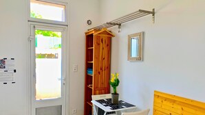 A compact room with a white door, a small table with a chair, a wooden cabinet, a drying rack, and a potted plant. - [2] Blue Summer Vibes Mini Studio, A/C, parking, 50m from beach, SPA access (La Ciotat)