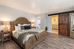 Ein Schlafzimmer mit einem hölzernen Bett, zwei Nachttischen, einem Schminktisch, einem großen Spiegel und einem Kleiderschrank.